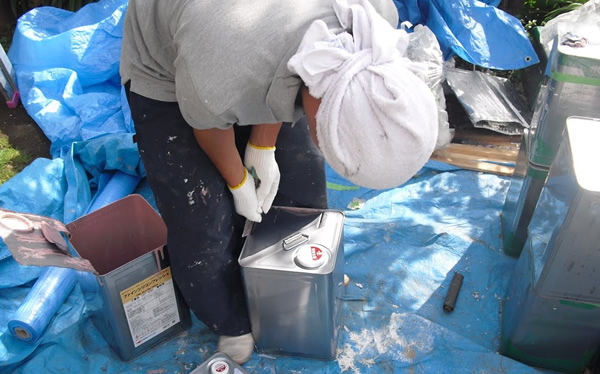 塗装職人が塗料缶を開けている様子